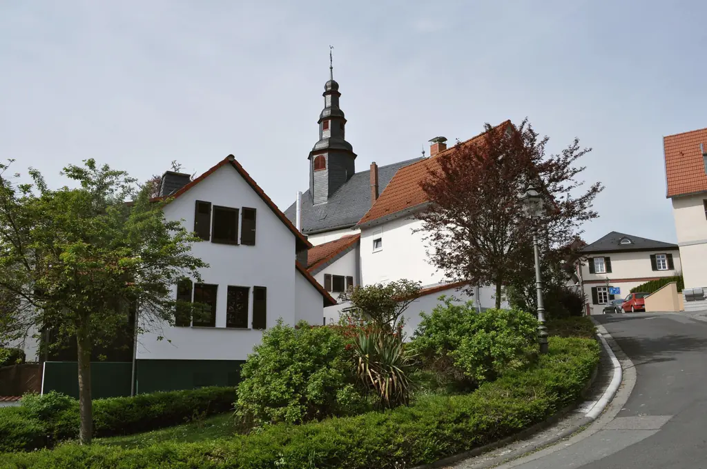 Weiße Wohnhäuser und der Kirchturm im Ortskern von Bad Vilbel-Dortelweil.