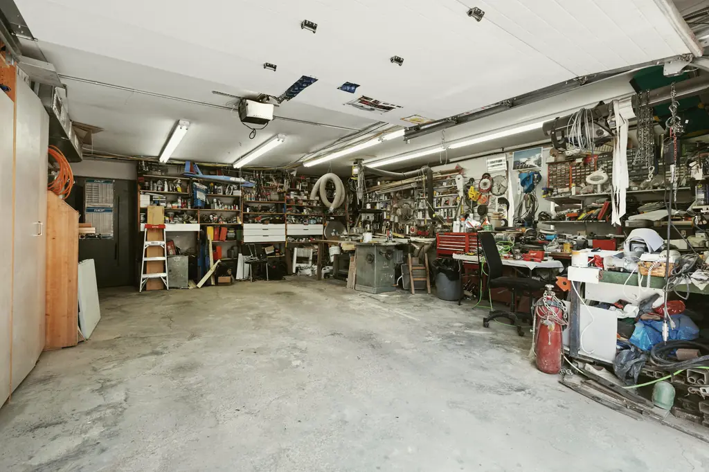 Vollgestellte Garage mit Werkbänken, Regalen, Werkzeug und allerlei Kram.
