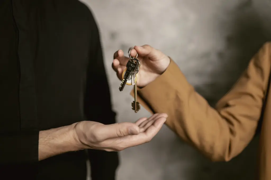 Eine Hand übergibt einen Schlüsselbund in die geöffnete Hand einer anderen Person.
